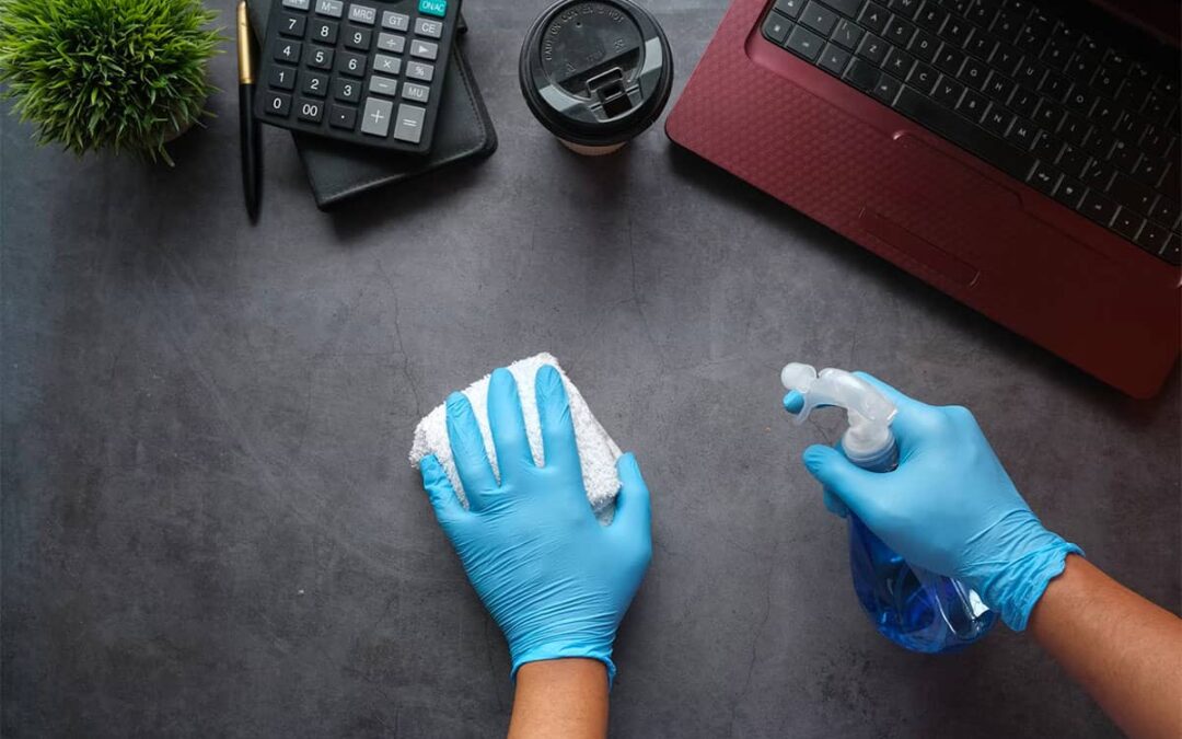 A person cleaning an office desk with eco detergent
